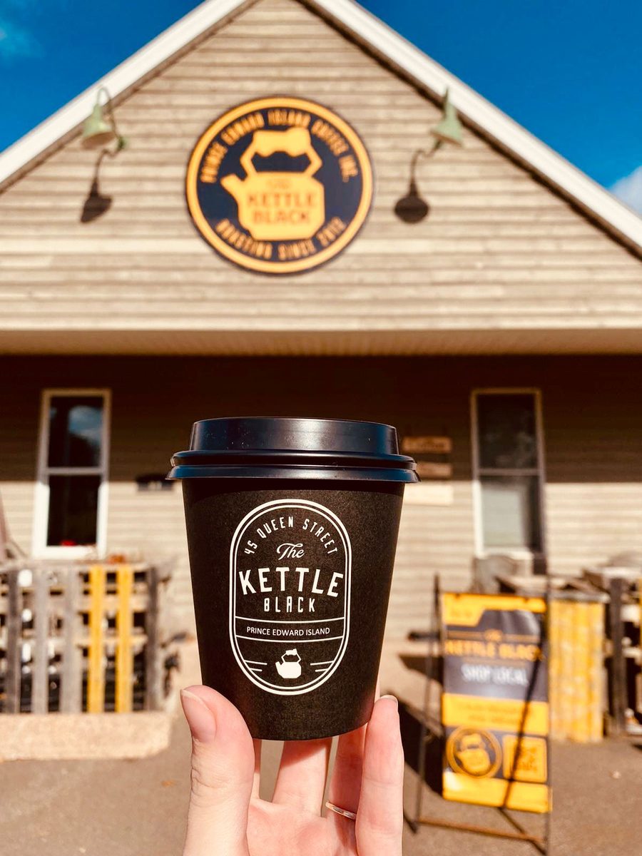 A Kettle Black takeout cup held up in front of the Stratford cafe